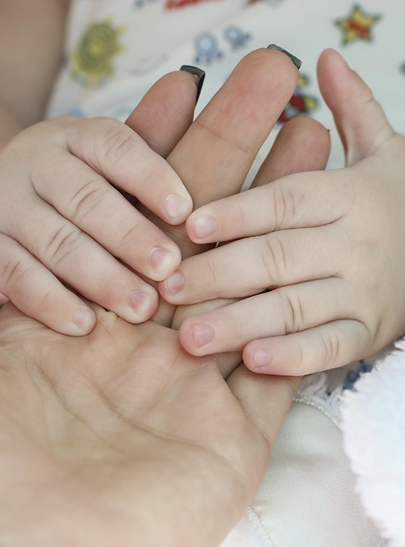 A close up shot of a young baby’s hands holding onto their parents hand