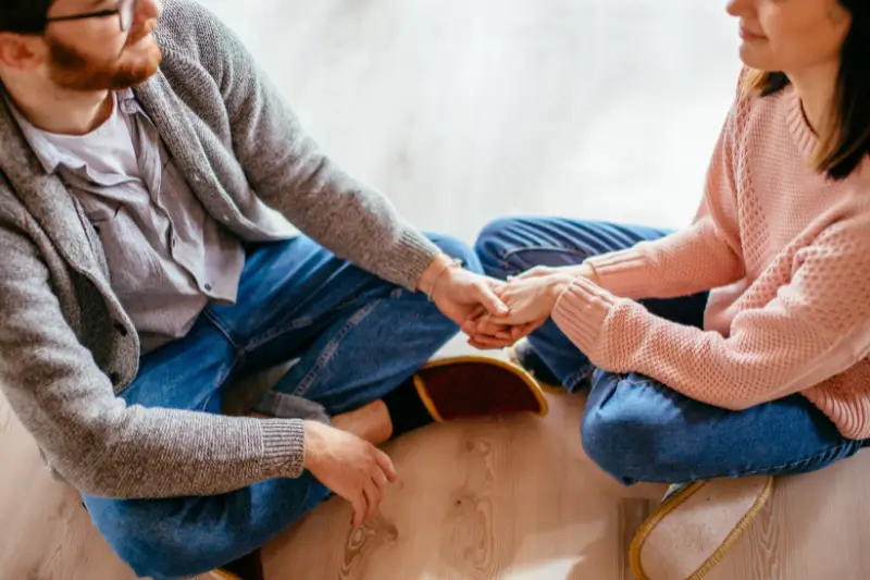 couple sitting together and holding hands while having infertility communication